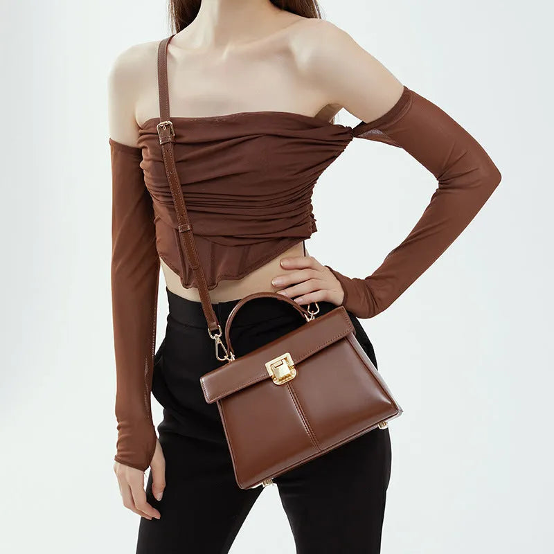 Black genuine leather women's shoulder bag with clasp closure showing square shape and adjustable strap
