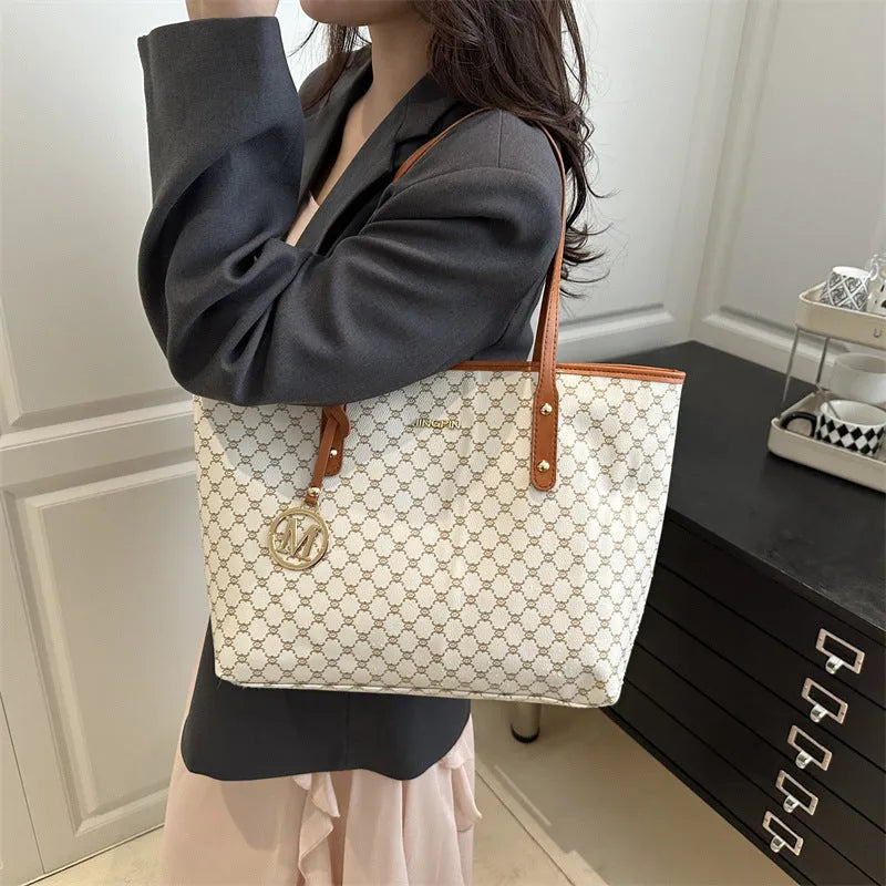 Women's black PU leather shoulder bag with sewing thread detail on a table.