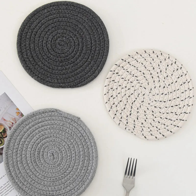 Set of three round grey cotton cord coasters on a wooden table