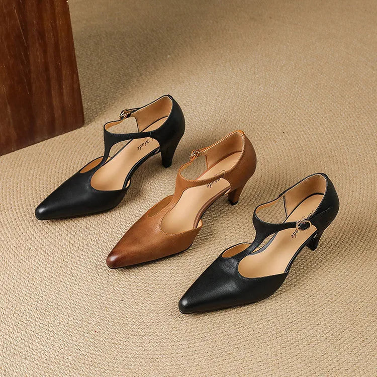 Brown retro women's T-strap sandals with a closed toe, low upper, and a stout high heel on a wooden floor.