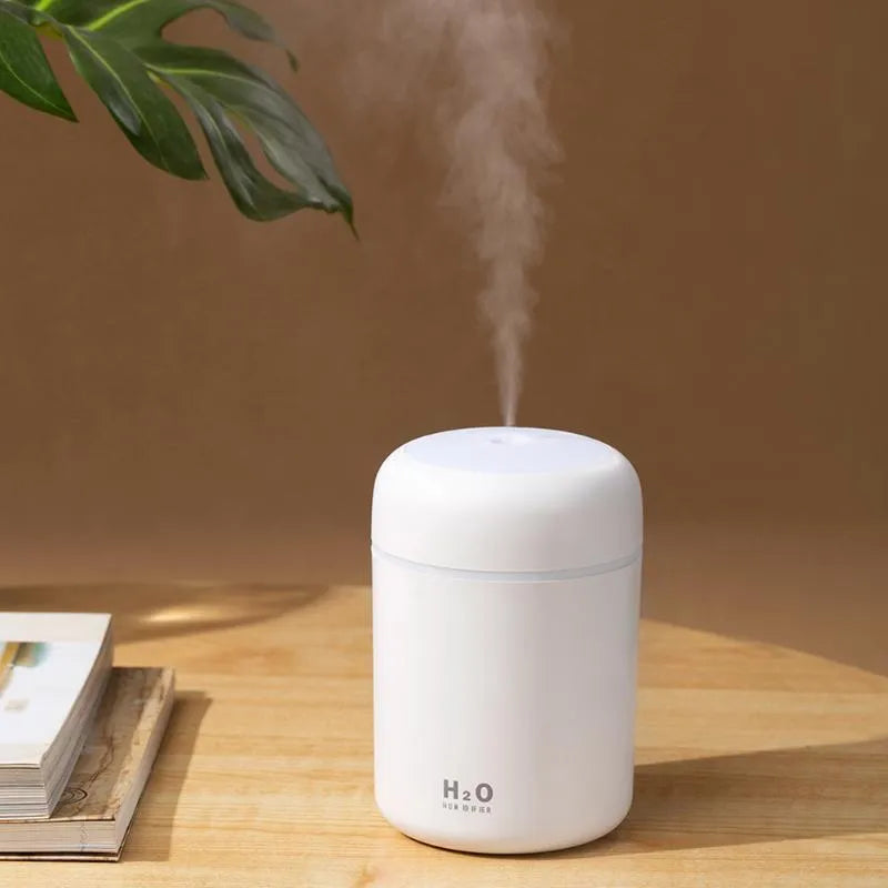 Pink USB portable humidifier with LED lights and water tank on wooden desk