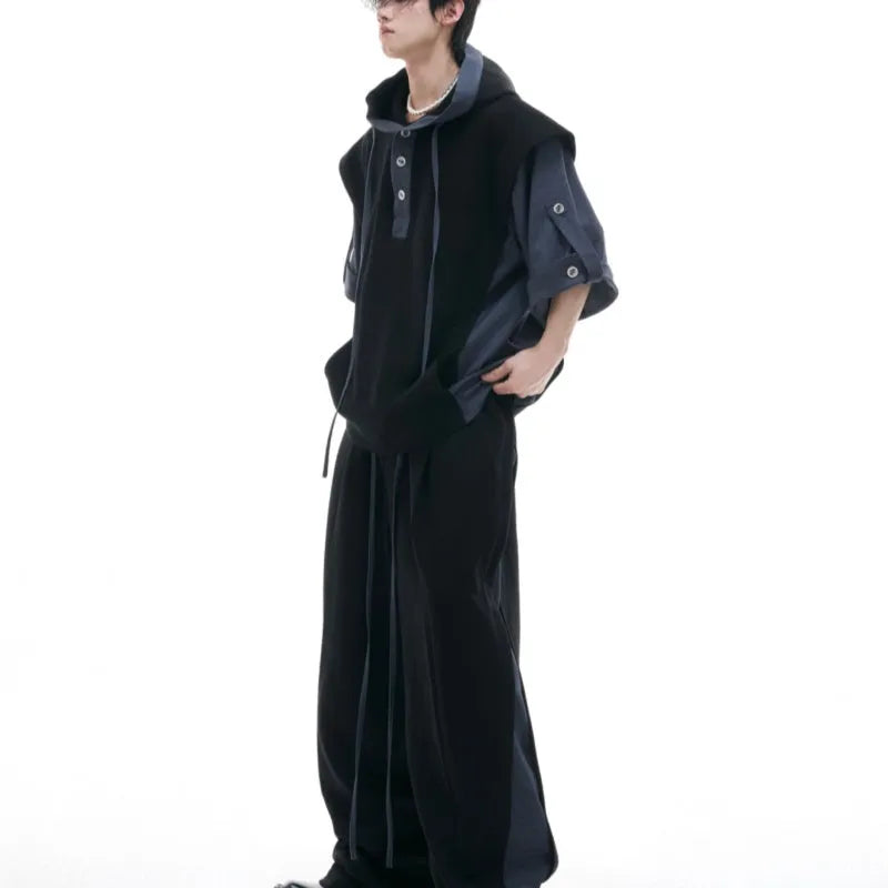 Man wearing a black hooded short-sleeve jacket and matching trousers from a polyester leisure suit.