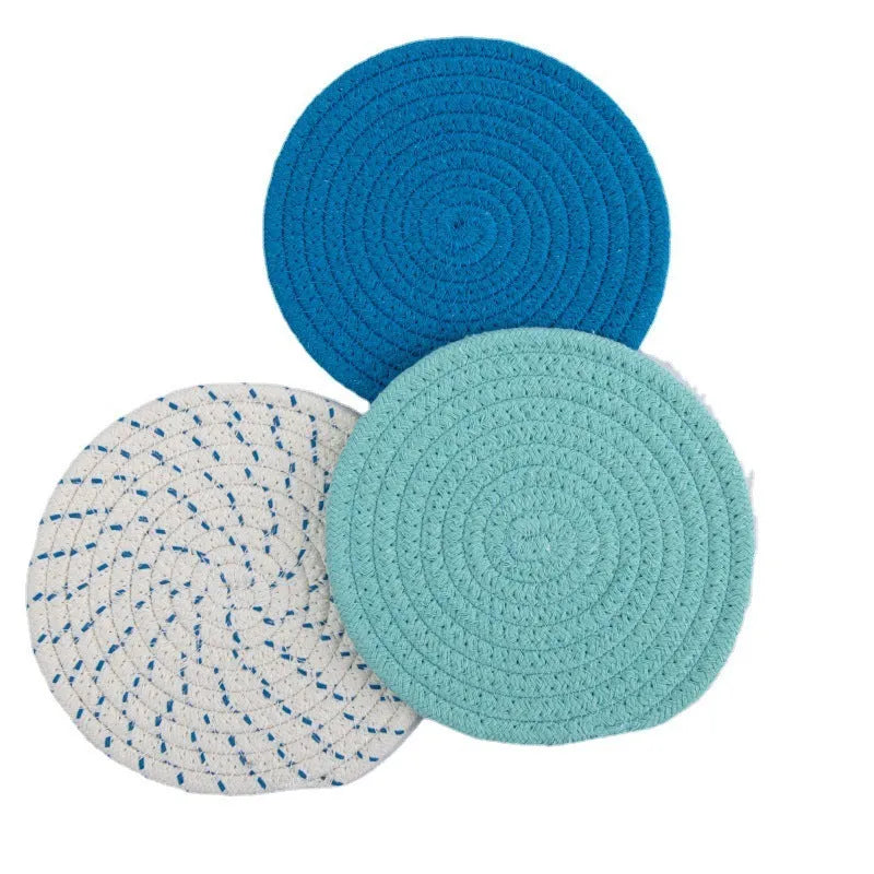 Set of three round grey cotton cord coasters on a wooden table