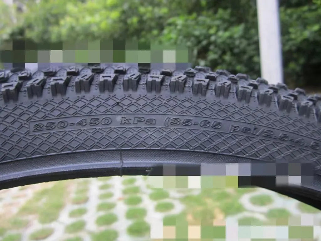 Ultralight black mountain bike tyre with white label sidewall option on a trail.