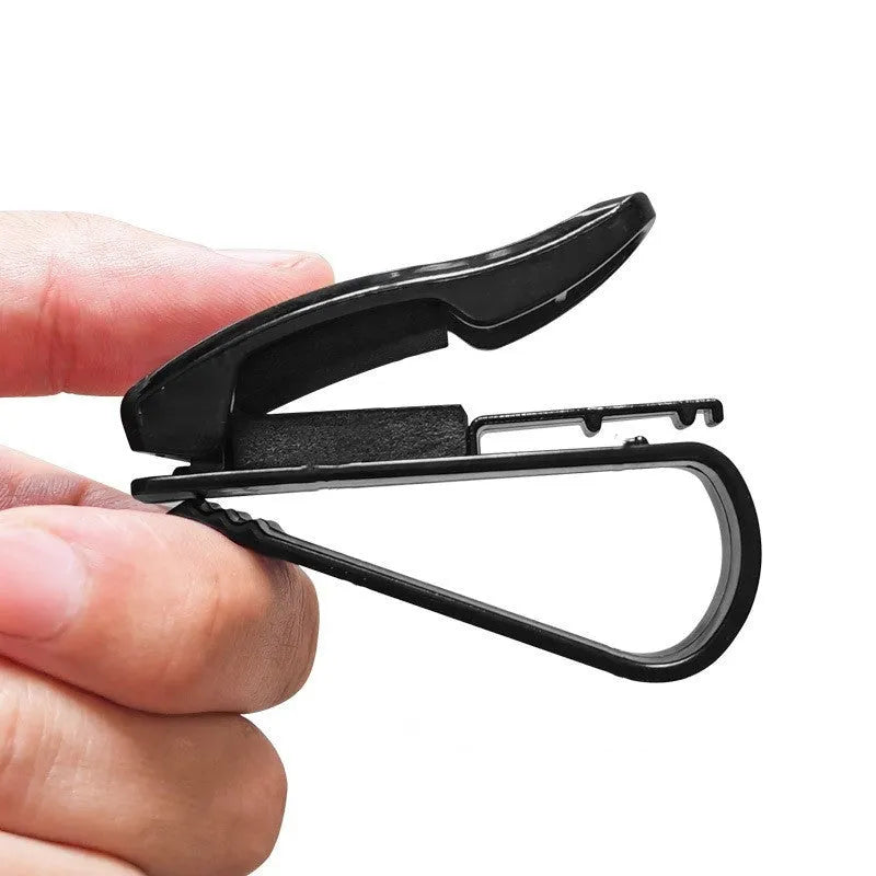 Black plastic car sun visor clip holding a pair of sunglasses and a parking ticket.