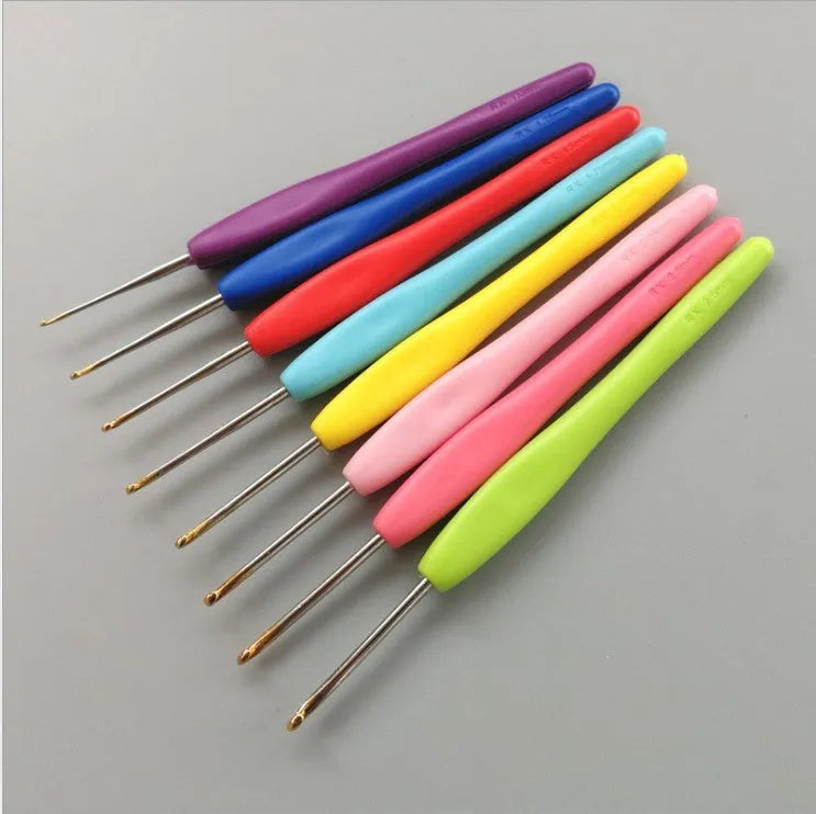 Set of 16 crochet hooks in various sizes with two handle types, laid next to a grey PU storage bag.