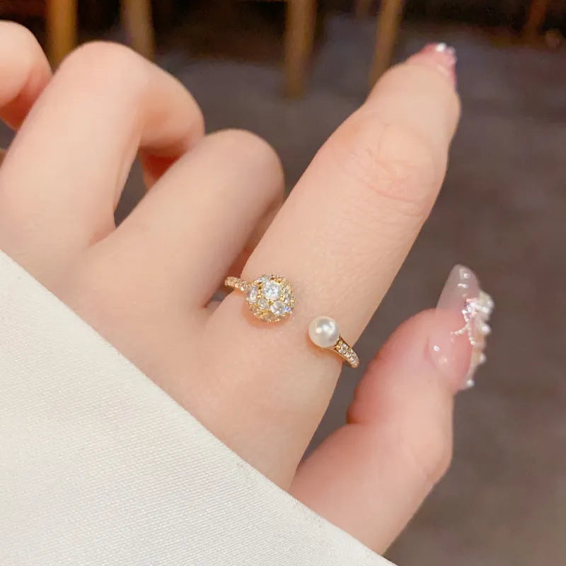 Open-end pearl ring with round zircon stones in gold plating on geometric copper base