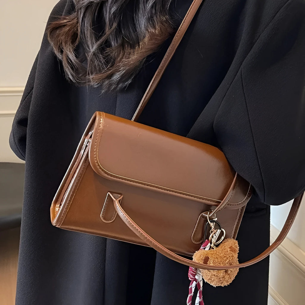 Brown women's PU leather crossbody shoulder bag with pendant, showing front view and adjustable double straps.