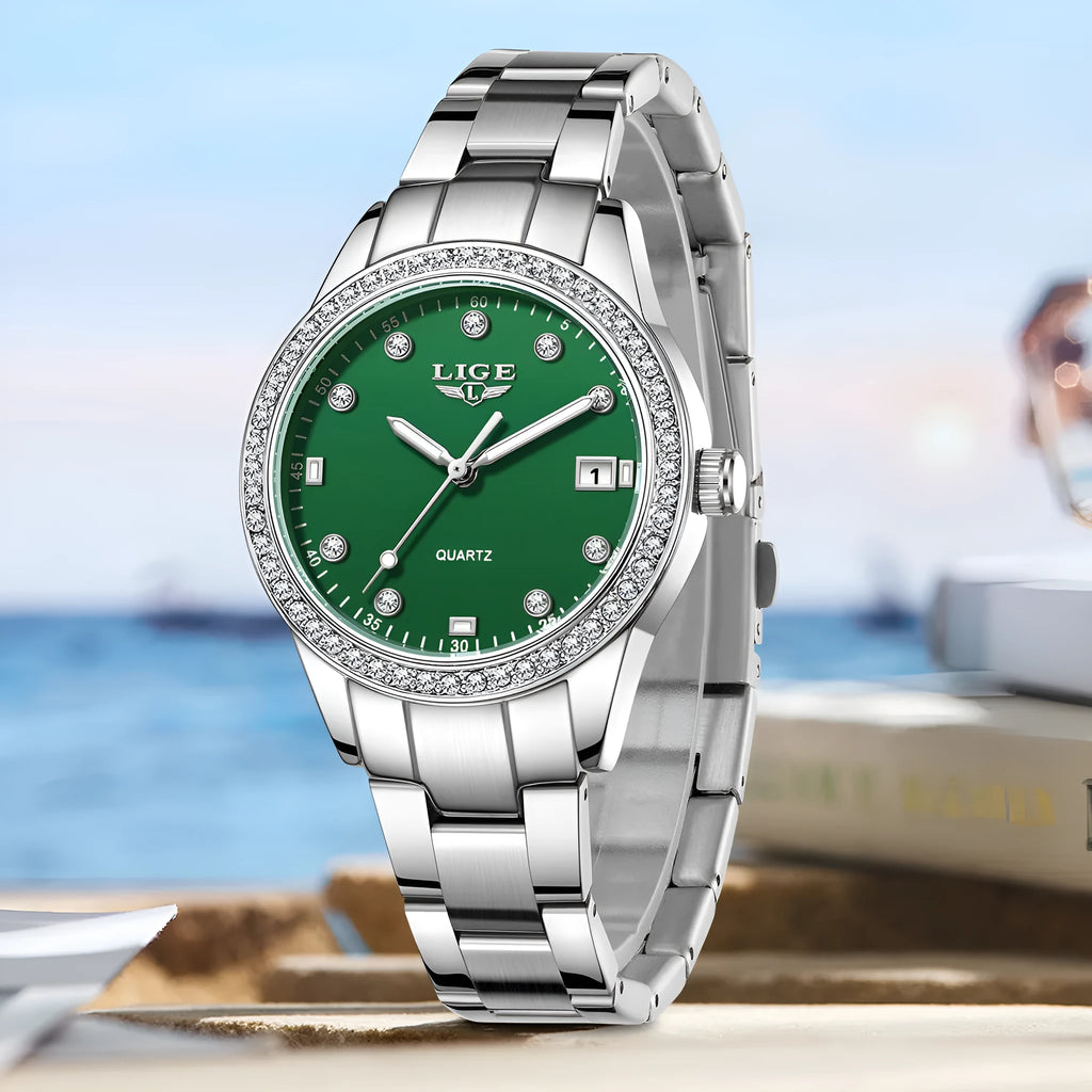 Silver fashion watch with diamond-encrusted round dial and luminous hands on a stainless steel strap.