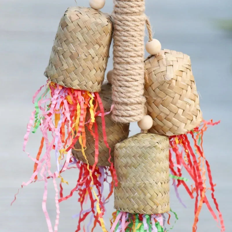 Wood and sisal rope parrot toy with colourful shredded paper hanging inside a bird cage.