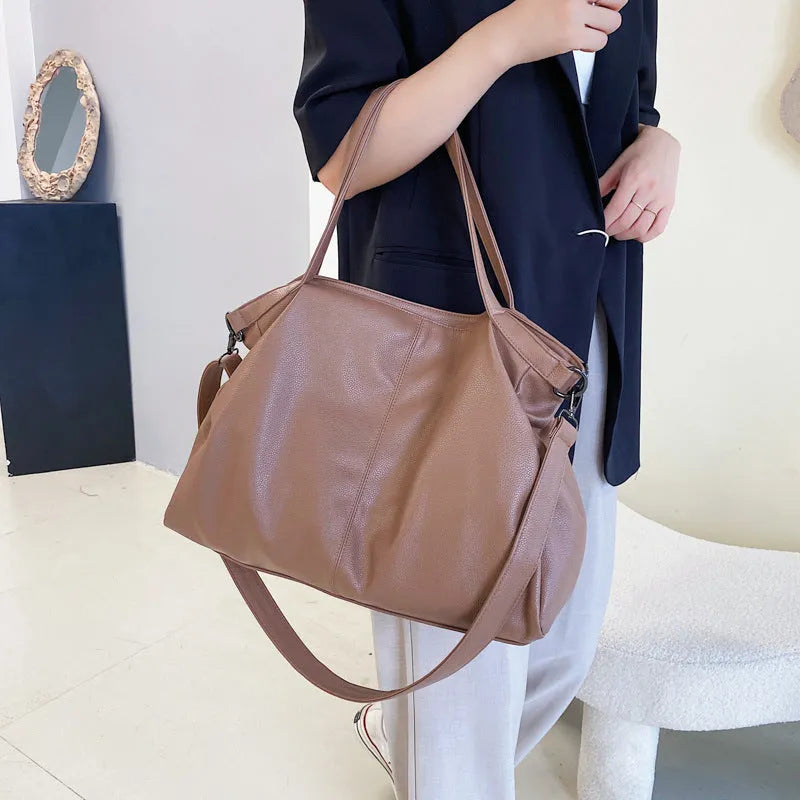 Large soft black PU leather messenger tote bag with a shoulder strap, showing zipper and phone pocket.