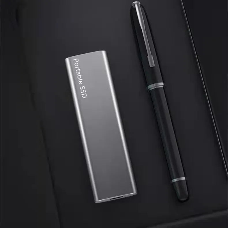 Ultra-thin metal portable external SSD drive in red, shown next to a laptop.