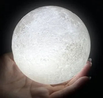 3D printed white moon lamp on a wooden stand, showing detailed craters and soft LED glow.