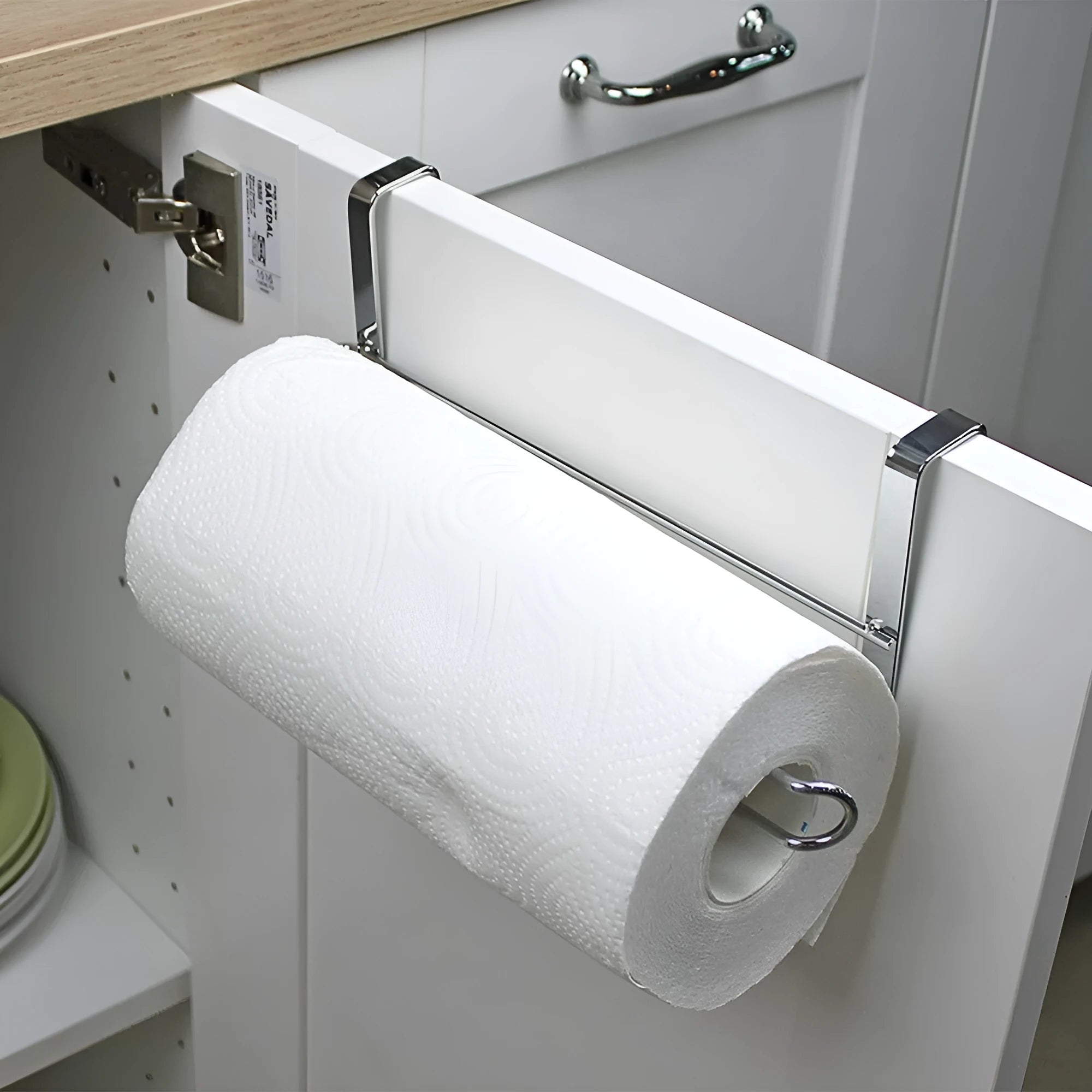 Silver stainless steel paper towel rack hanging over cabinet door for kitchen storage
