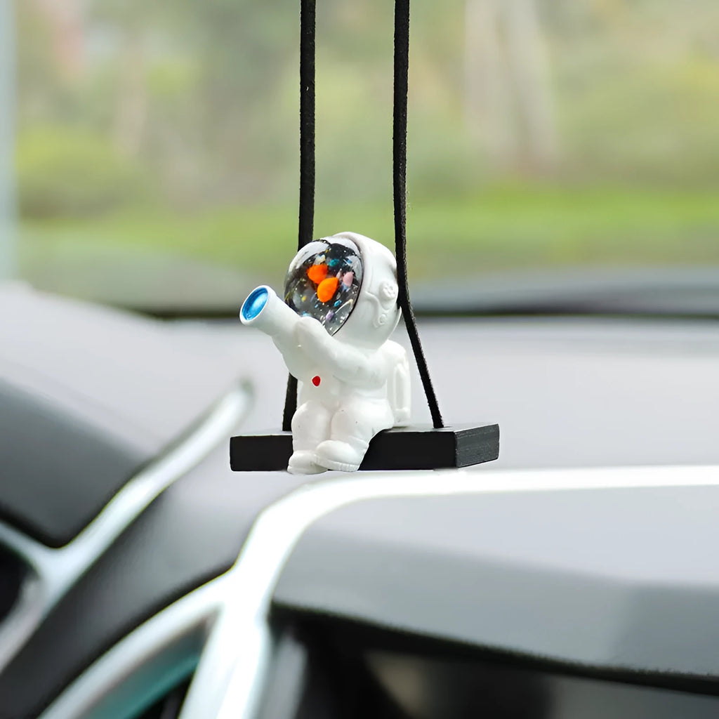 Resin cartoon astronaut car pendant charm in red flag design hanging from a rearview mirror.