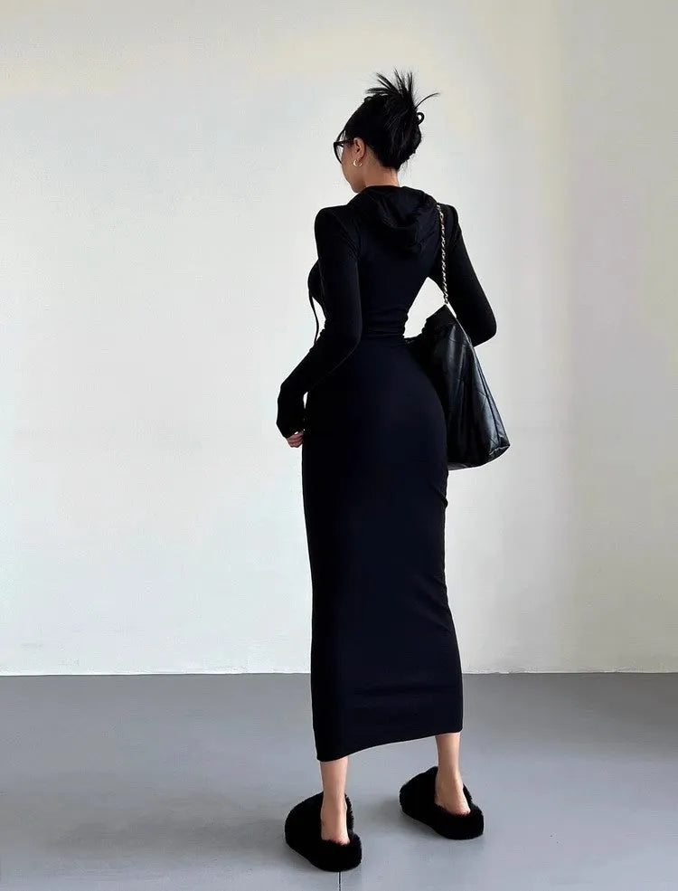 A woman wearing a light grey hooded long sleeve sheath dress with a high waist.