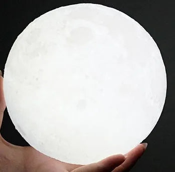 3D printed white moon lamp on a wooden stand, showing detailed craters and soft LED glow.