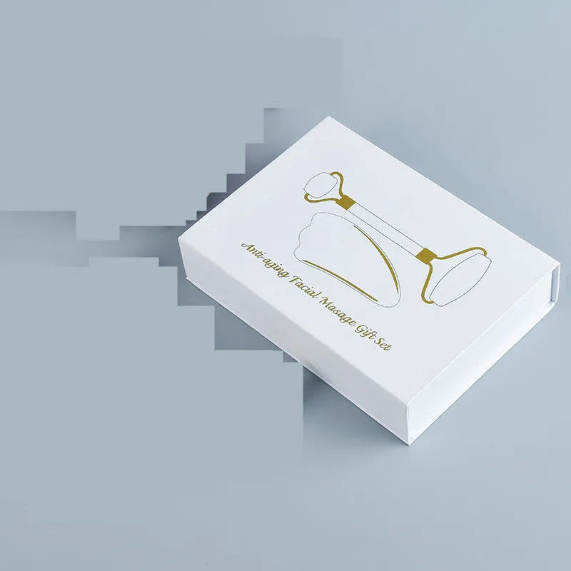 White jade facial roller and matching massage board set on a flat surface.