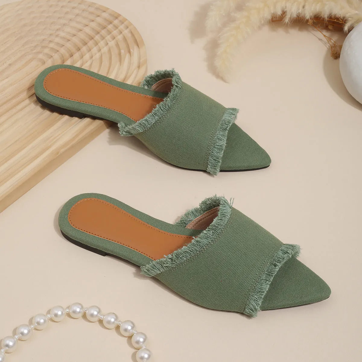Women's denim flat slippers with tassel detail in apricot colour on a white background.