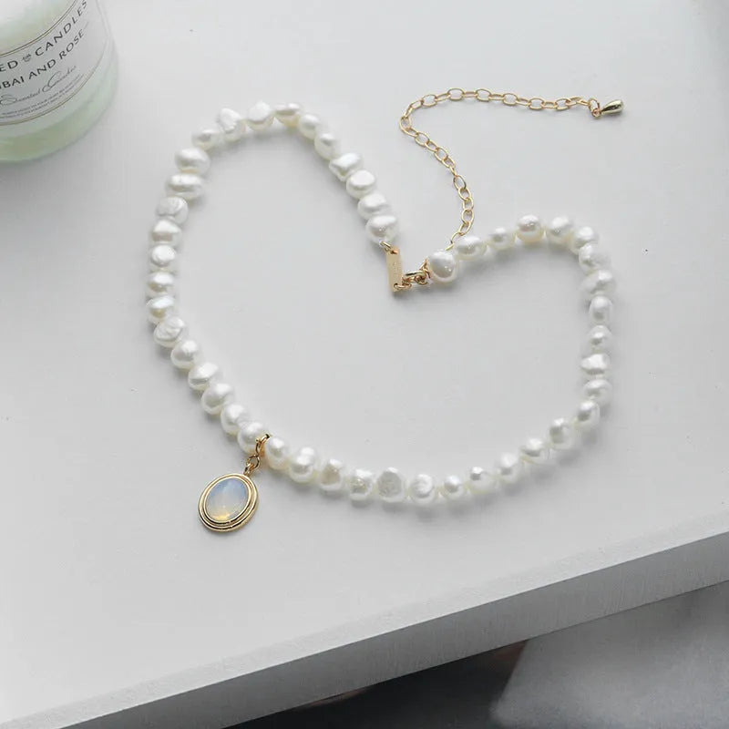 Round medal pearl necklace with geometric silver pendant and irregular pearls on a silver chain.