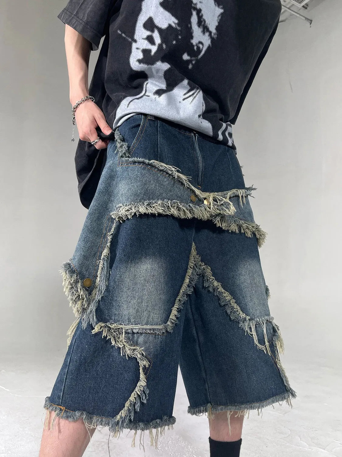 Blue denim shorts with a frayed five-pointed star detail on the leg, showing a loose, retro fit.