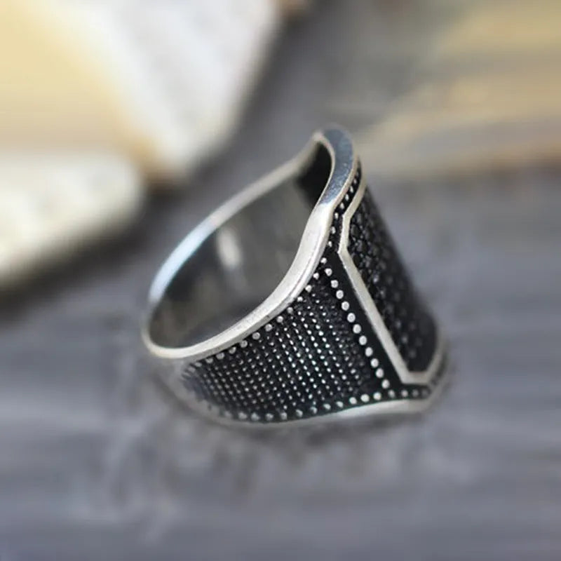 Black alloy ring with copper inlays holding zircon stones, shown on a finger.