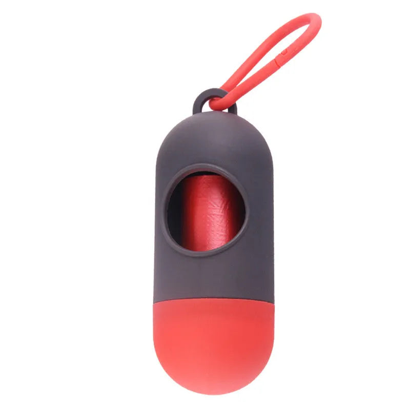 Compact black dog poop bag dispenser with side hook and Velcro strap, shown next to a roll of waste bags.