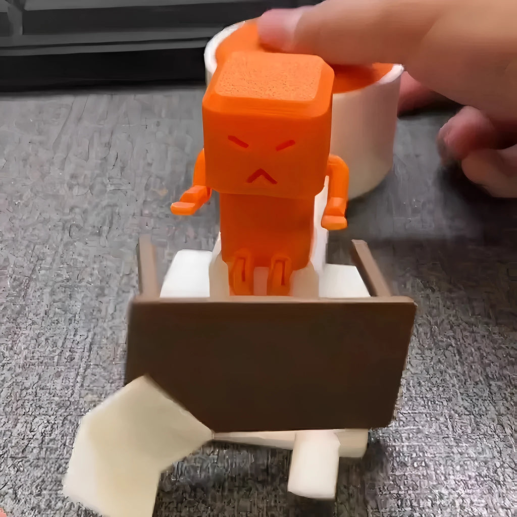 Orange plastic Take a Shot vent decompression toy with a rotating table on a desk.
