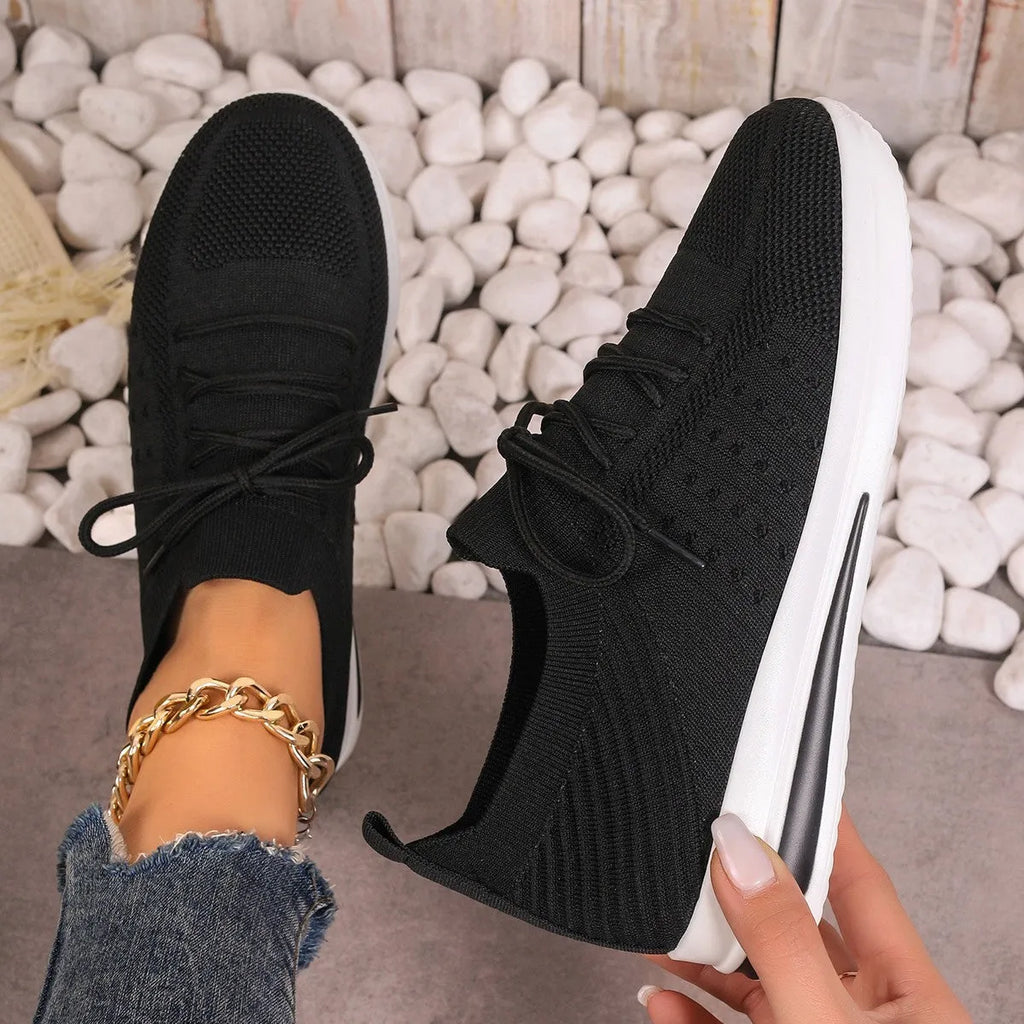 Women's red fly-knit lace-up sneakers with a low-top round-toe design on a white background.