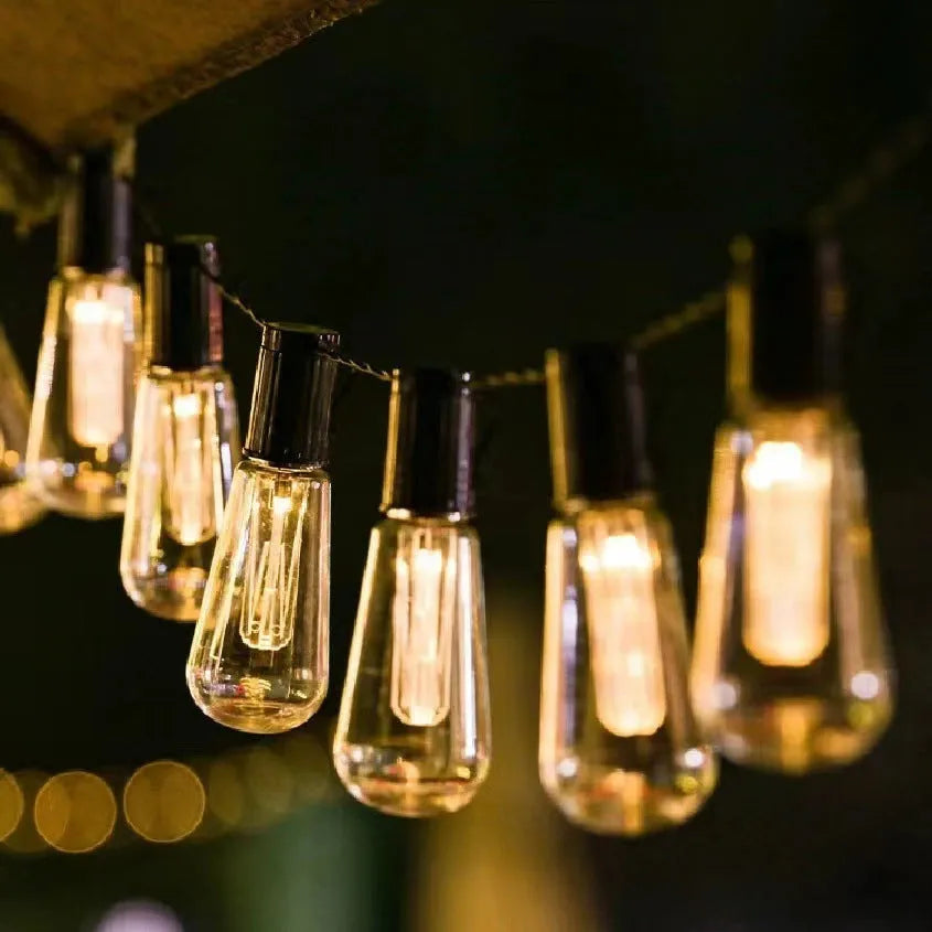Retro infusion bottle shaped glass bulb outdoor string lights in garden setting