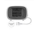 Mini green desktop heater with metal grille showing compact size on a wooden desk