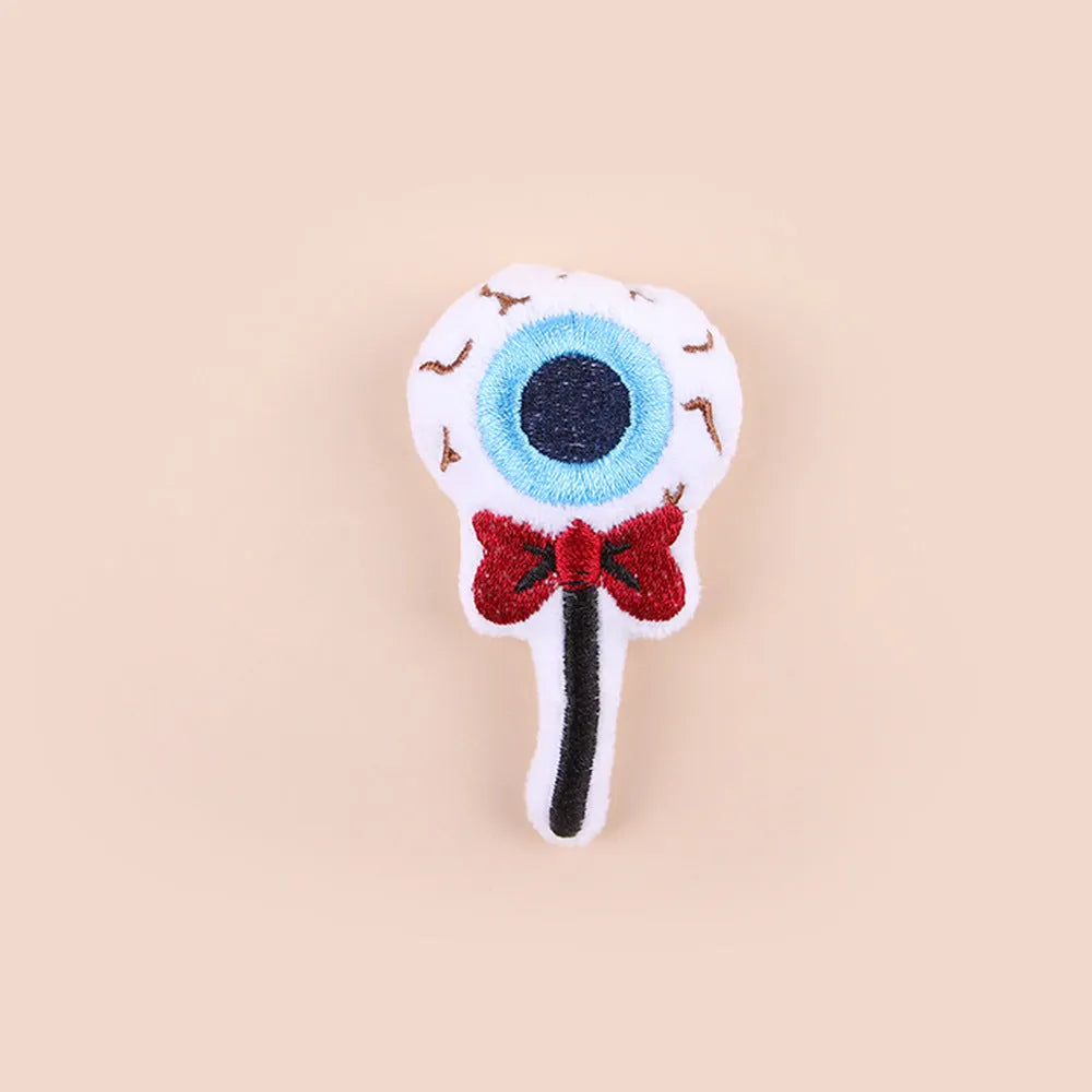 Small plush cat teaser wand with three interchangeable attachments: candy, eyes and skull designs