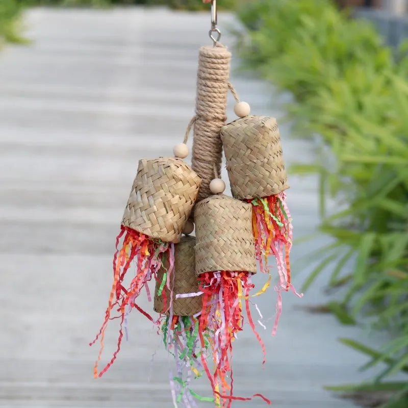 Wood and sisal rope parrot toy with colourful shredded paper hanging inside a bird cage.