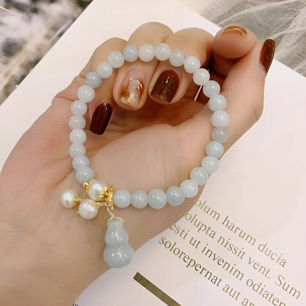 A handcrafted natural emerald jade bracelet with a detailed gourd charm, presented on a white background.