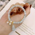 A handcrafted natural emerald jade bracelet with a detailed gourd charm, presented on a white background.