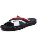 Men's cowhide leather beach flip-flops with non-slip sole in black, on a sandy background.