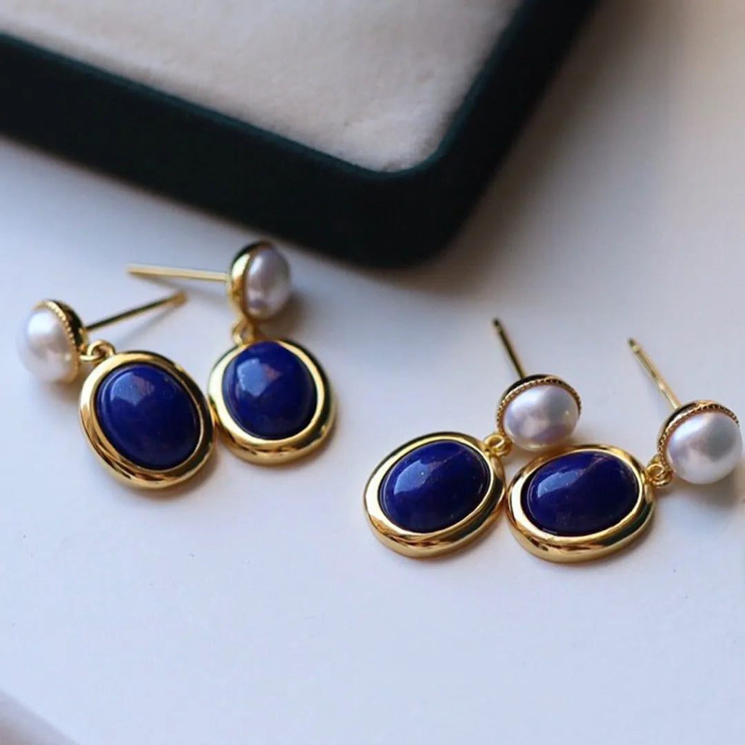A pair of simple stud earrings with blue lapis lazuli pearls set in silver backings featuring auspicious patterns.