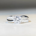Silver geometric cross ring with a 1 karat moissanite stone and twisted band.
