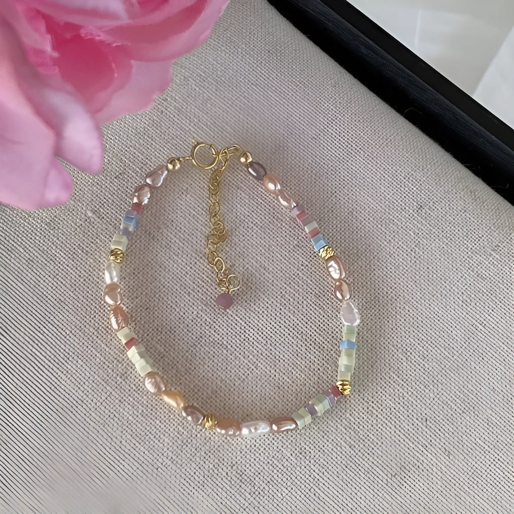 Close-up of a women's mini bracelet with irregular natural pearls set in 14K gilded purple silver, shown with its matching necklace.