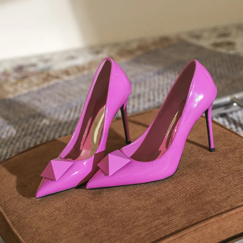 Pink patent leather women's stiletto heels with pointed toe, ankle strap buckle and rivet details.