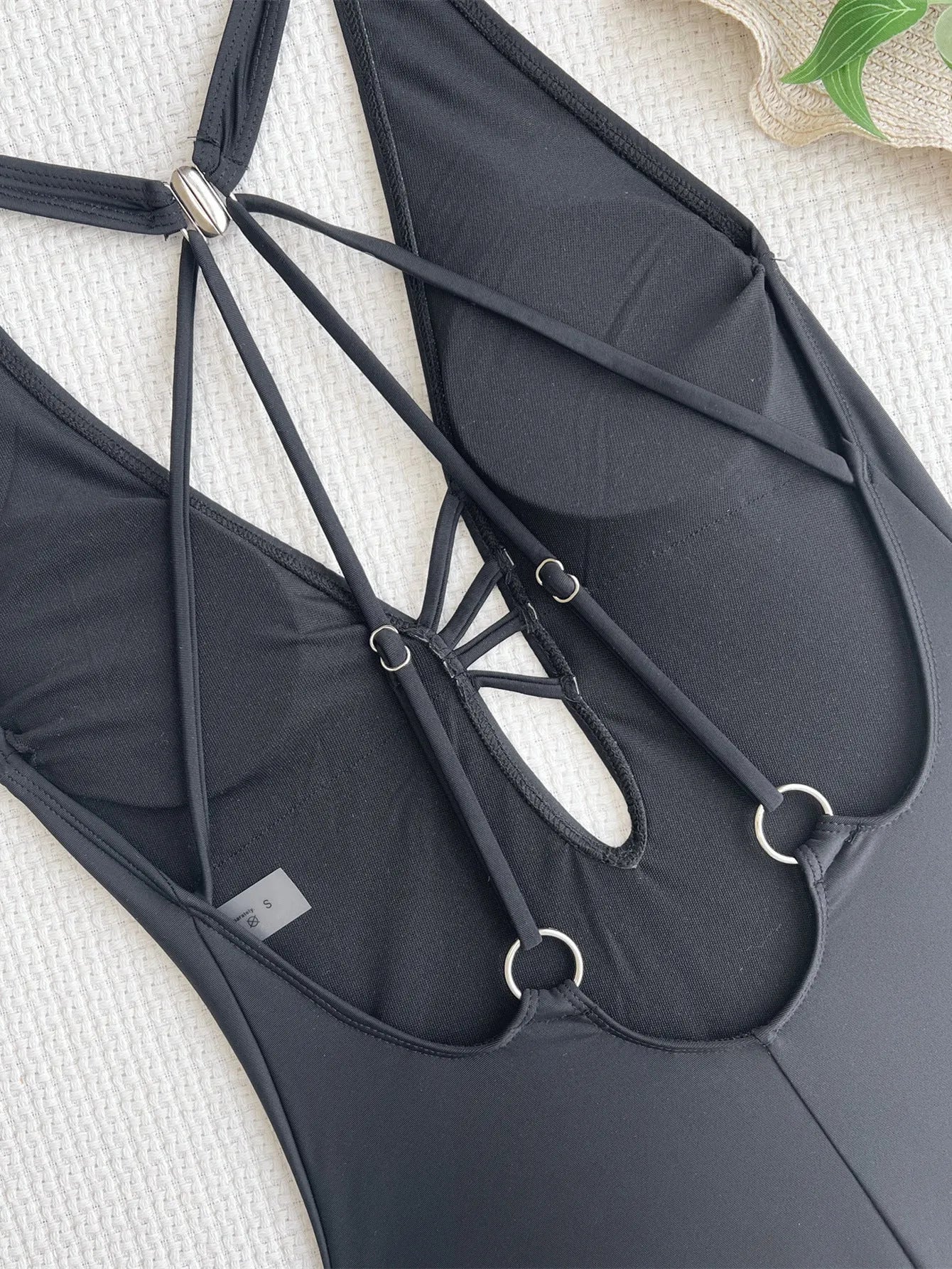 Black solid colour ladies one-piece nylon swimsuit laid flat.