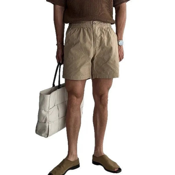 Man wearing loose-fit black cotton sports shorts on a summer day.