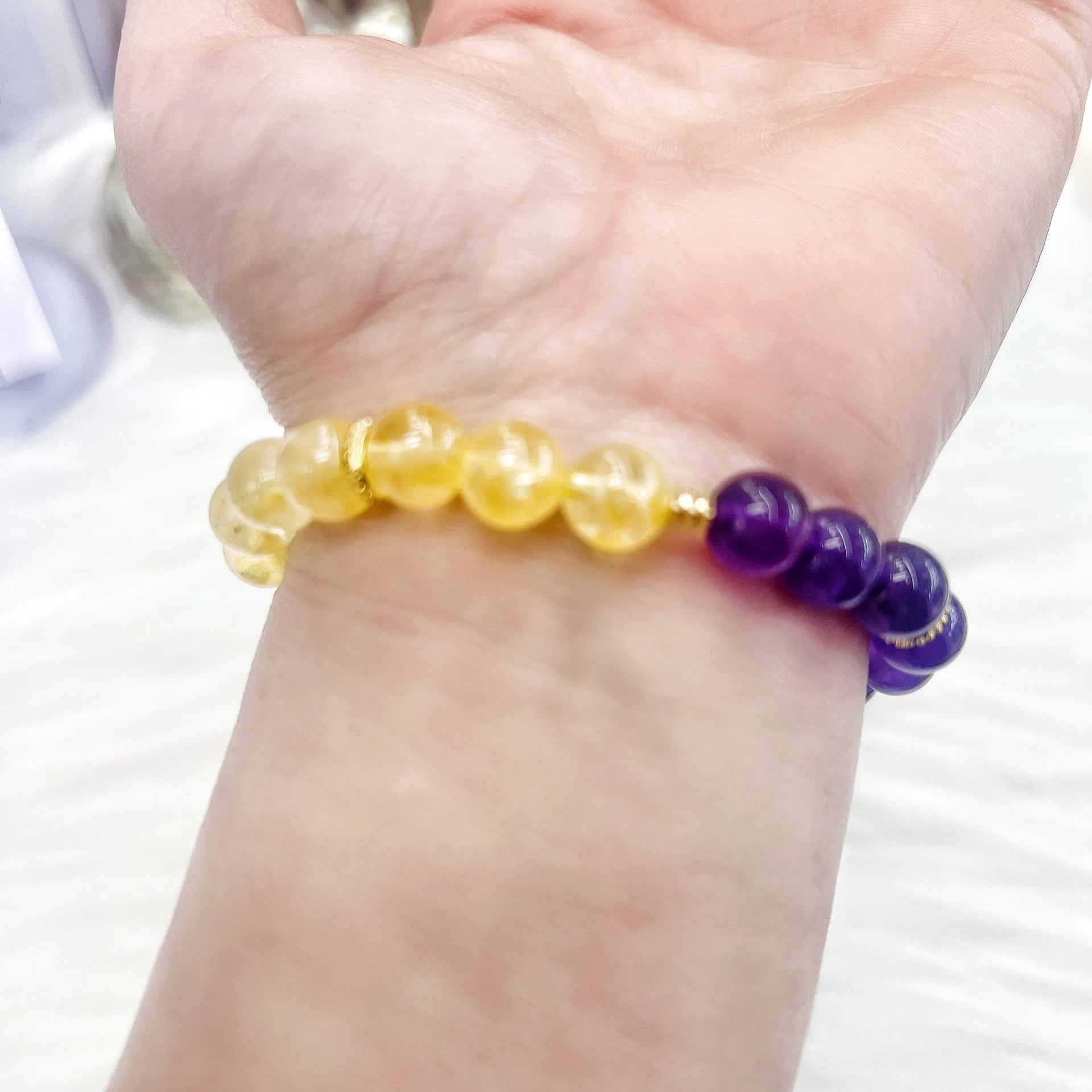 Handmade yellow and purple crystal women's bracelet on wrist.
