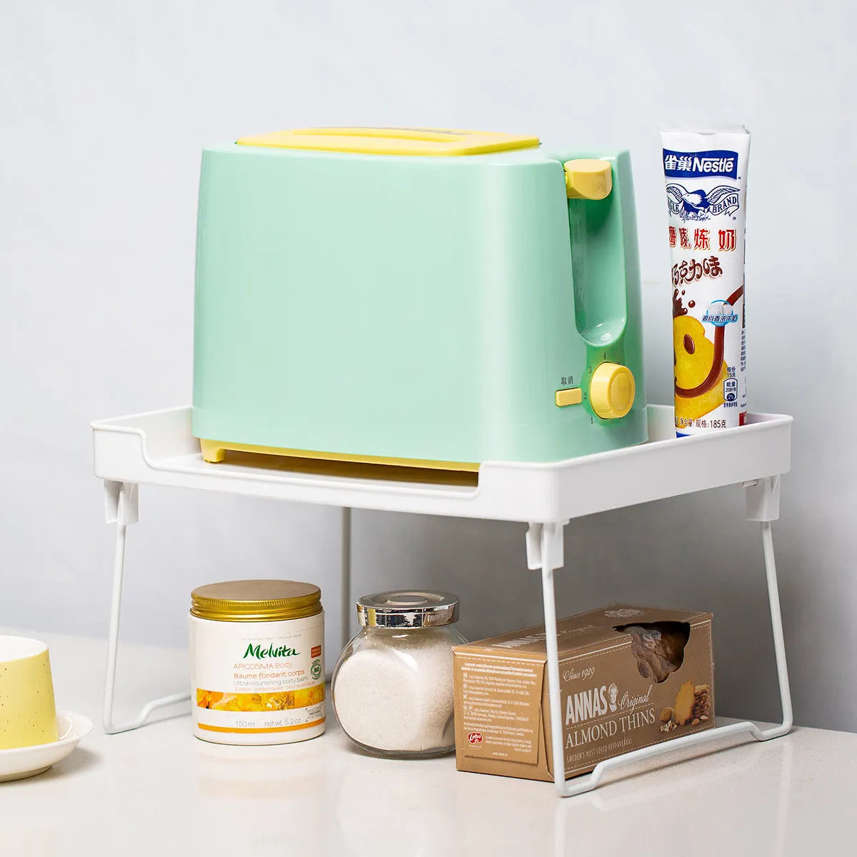 White plastic kitchen supplies rack holding bottles and jars on a countertop