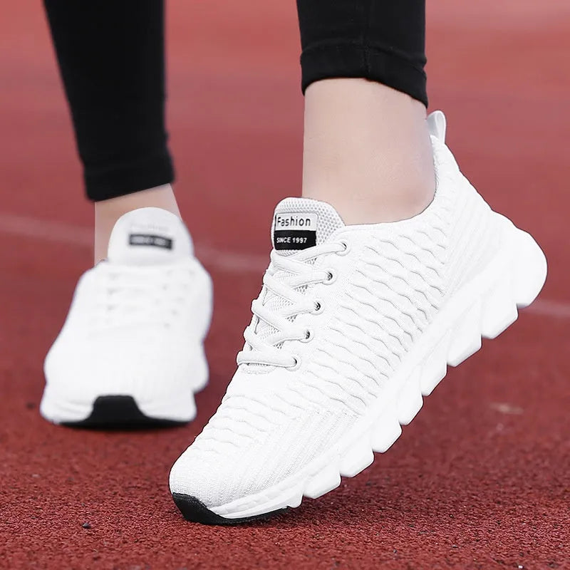 Women's running shoes in black, pink, or white with a breathable fly knit upper and durable outsole.