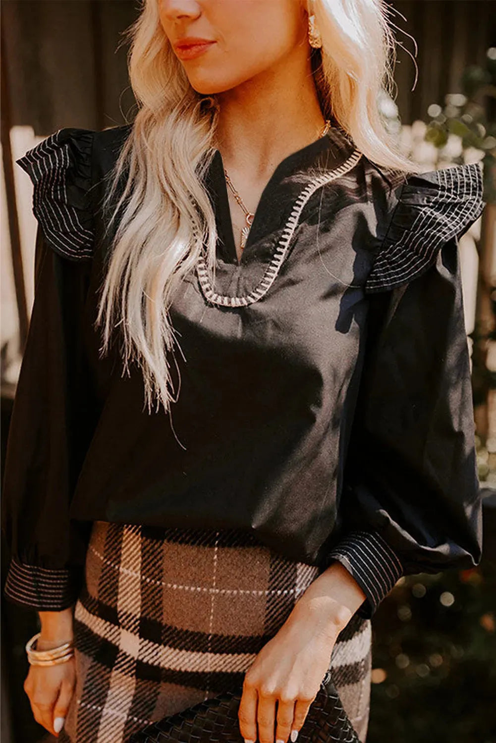 Black V-neck blouse with contrast stitching and ruffle long sleeves on hanger