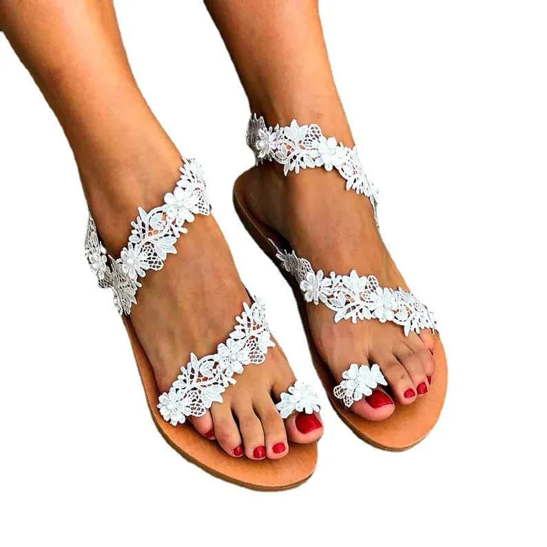 White women's flat sandals with rhinestone and floral decoration on the strap.
