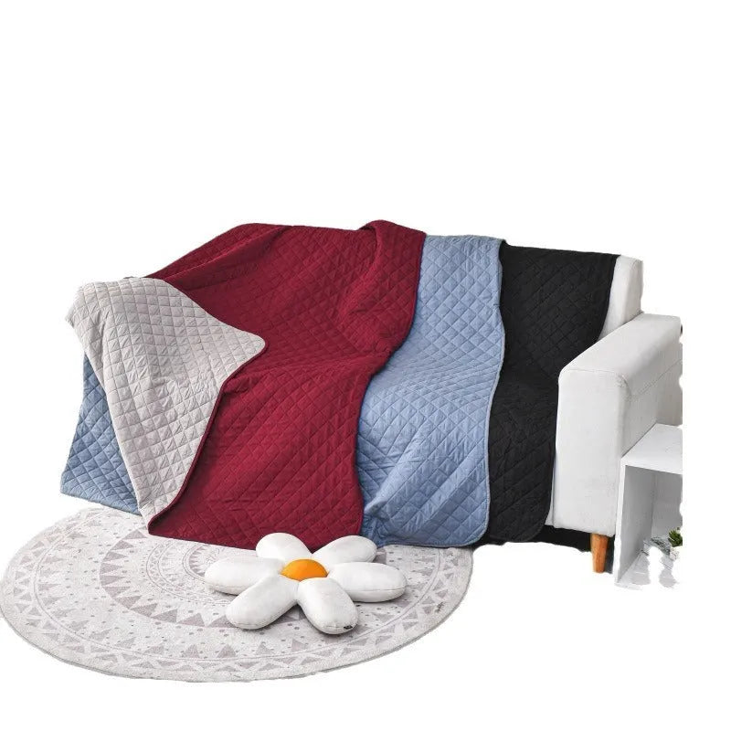 Reversible dog blanket on a sofa showing two colour sides, available in multiple sizes.