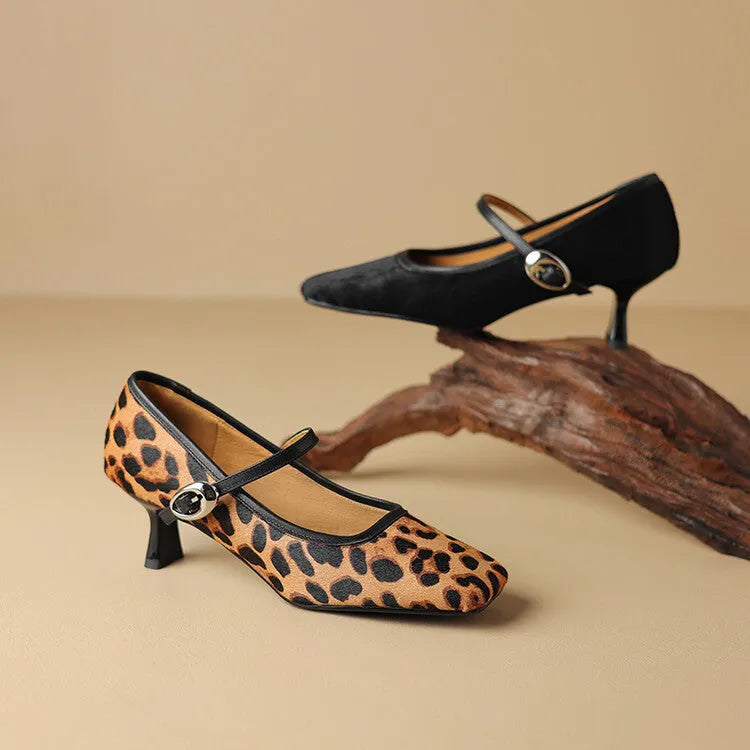 Women's black square toe stiletto heel ankle-strap shoes with horse hair upper on a neutral background.