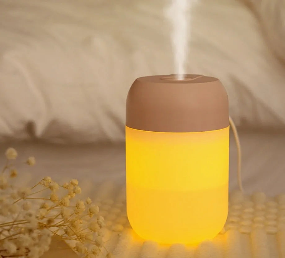 White cylindrical mini humidifier with USB cable on wooden desk